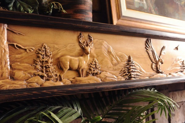 Wildlife Chorus fireplace mantel closeup with 8 point buck and eagle mountain scene.