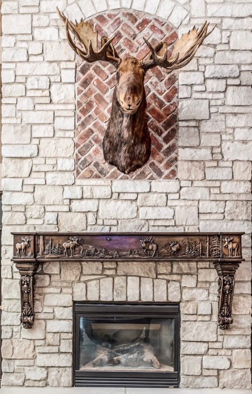 Moose Head mounted over a carved moose fireplace mantel.